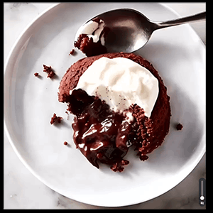 Two molten Guinness chocolate lava cakes dusted with powdered sugar, one cut open to show the gooey chocolate center
